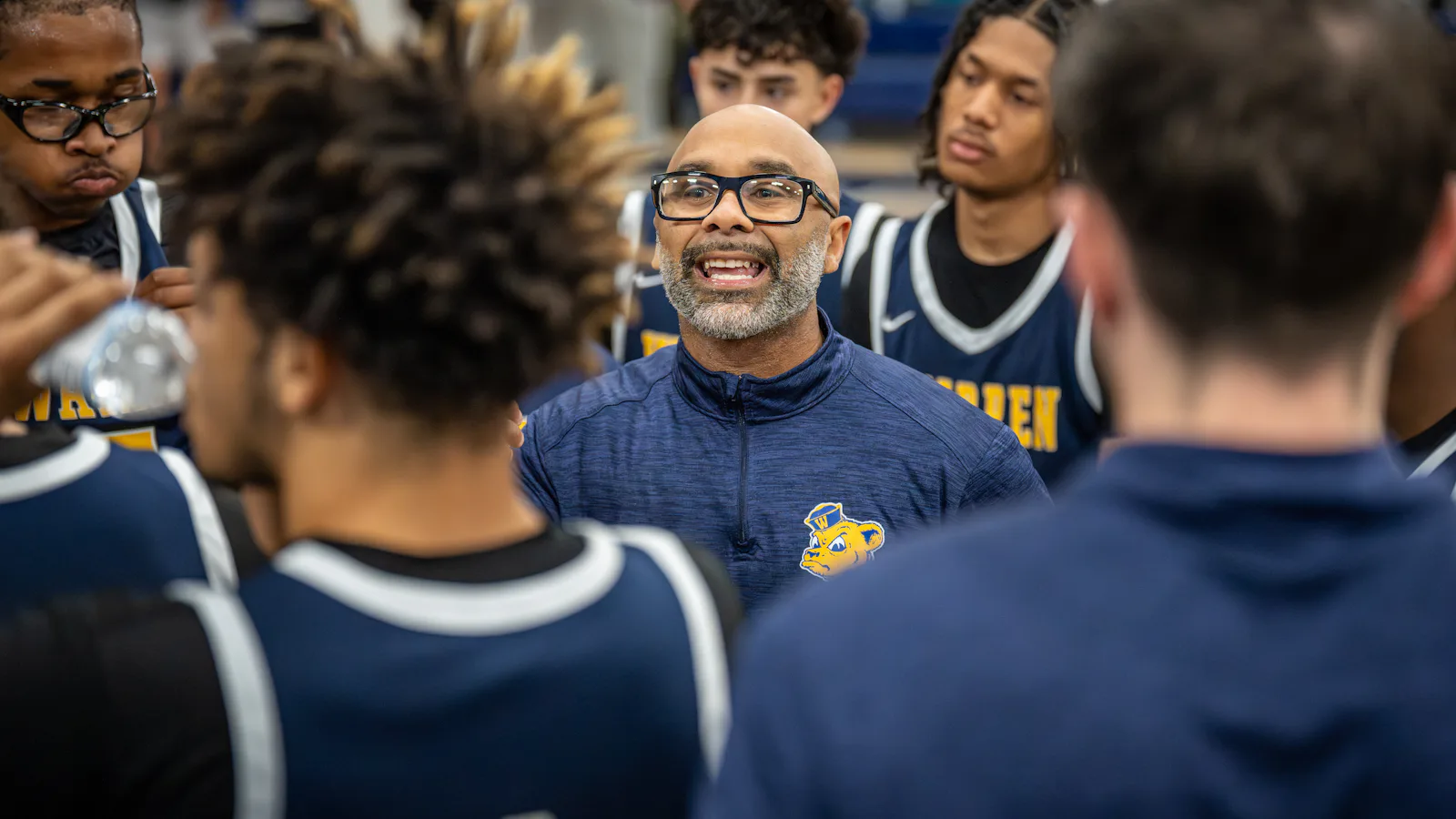 Coach donnant ses consignes aux joueurs de basket en cercle - briefing équipe