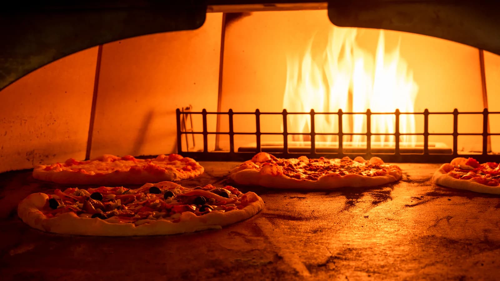 Pizzas en cuisson dans un four à bois - équipement pizzeria