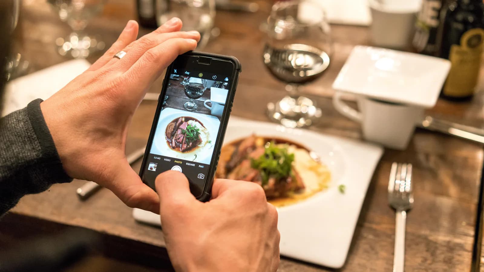 Personne qui prend en photo un plat avec son téléphone, contenu social food
