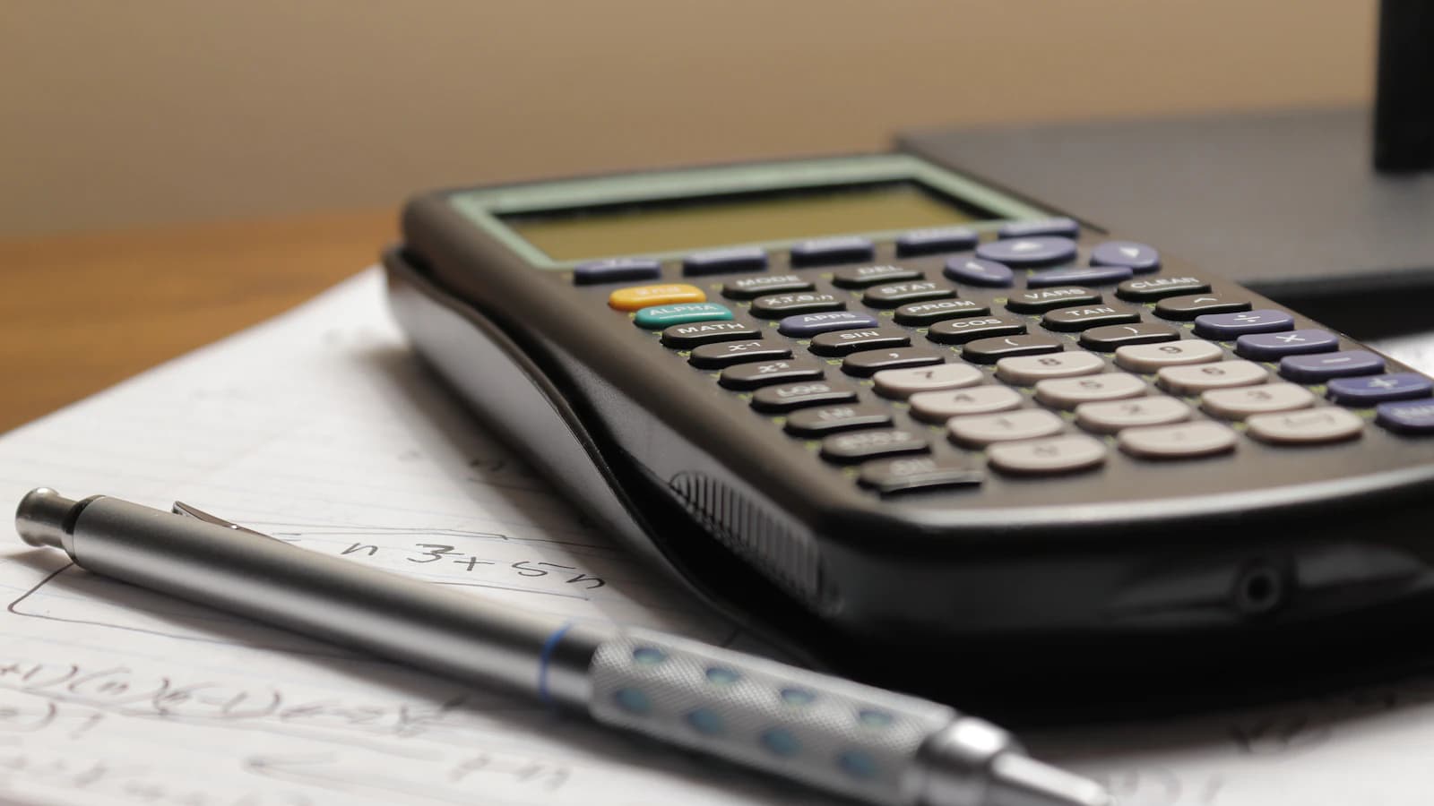 Calculatrice et stylo sur feuille de papier, gestion comptable et pilotage marge pizzeria